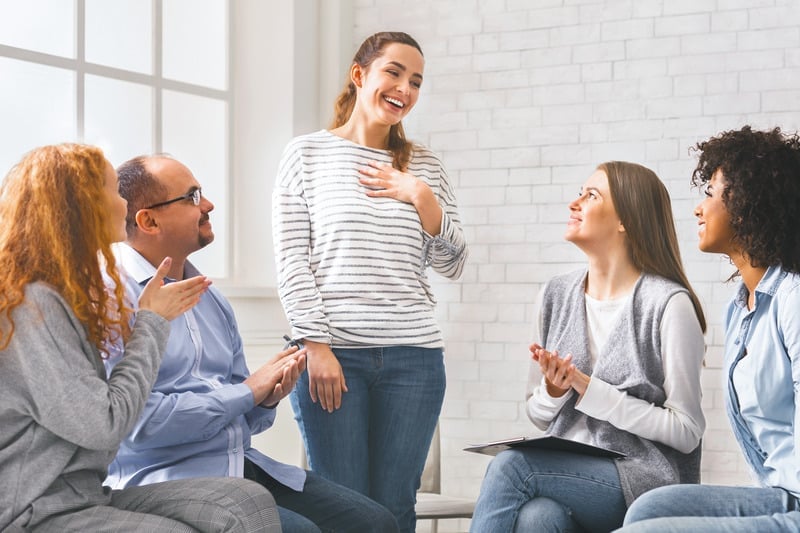 Happy woman standing, being welcomed at a support group meeting