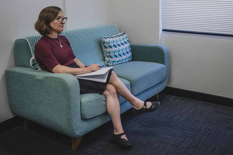 Clinical Psychologist, Jane Zimmerman sitting on a light blue couch during a consultation with a client